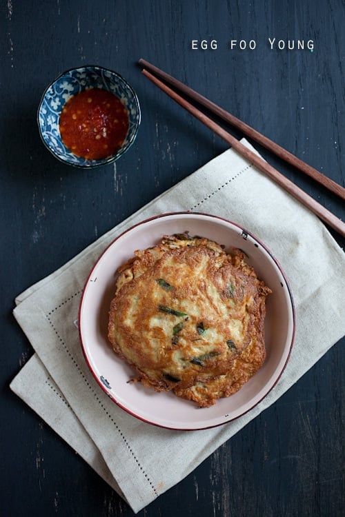 Delicious Chinese omelet, egg foo young, with pork and vegetable filling. Popular egg dish that is placed on a plate with hot sauce on the side.