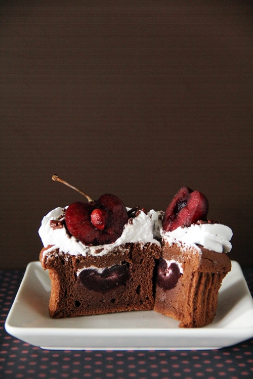 Cupcakes della foresta nera fatti con cioccolato, ciliegie e panna montata, a metà, pronti da servire.