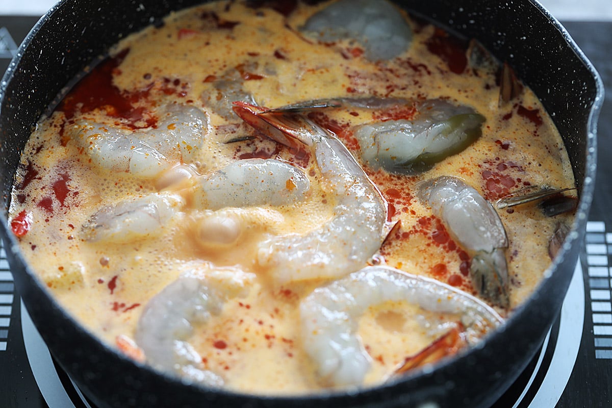 Cooking pineapple shrimp curry in a small pot. 