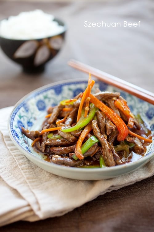 Easy and delicious Asian beef stir fry in mild spicy Szechuan sauce, served in a plate with a pair of chopsticks.