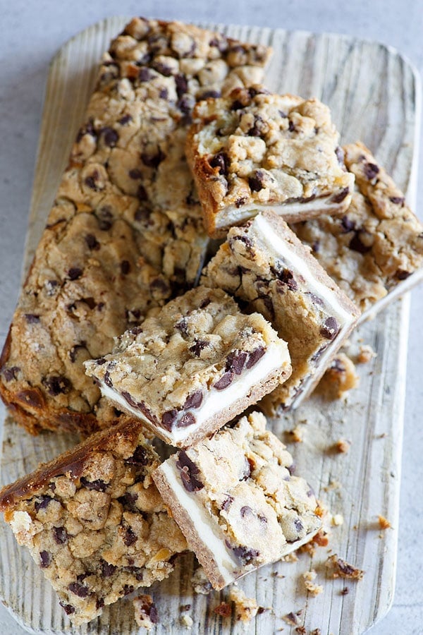 Easy and quick Chocolate Chip Cookie Dough Cheesecake Bar cut and stacked on a wooden chopping board.