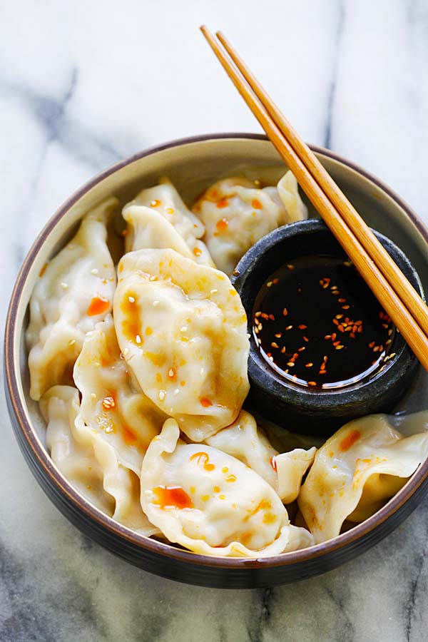 Easy and quick Chinese dumplings filled with pork, shrimp and napa cabbage served in a bowl with a pair of chopsticks.