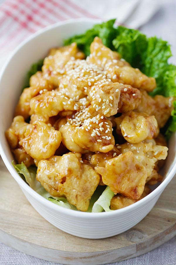 Crispy honey lemon chicken topped with sesame seeds in a serving dish.