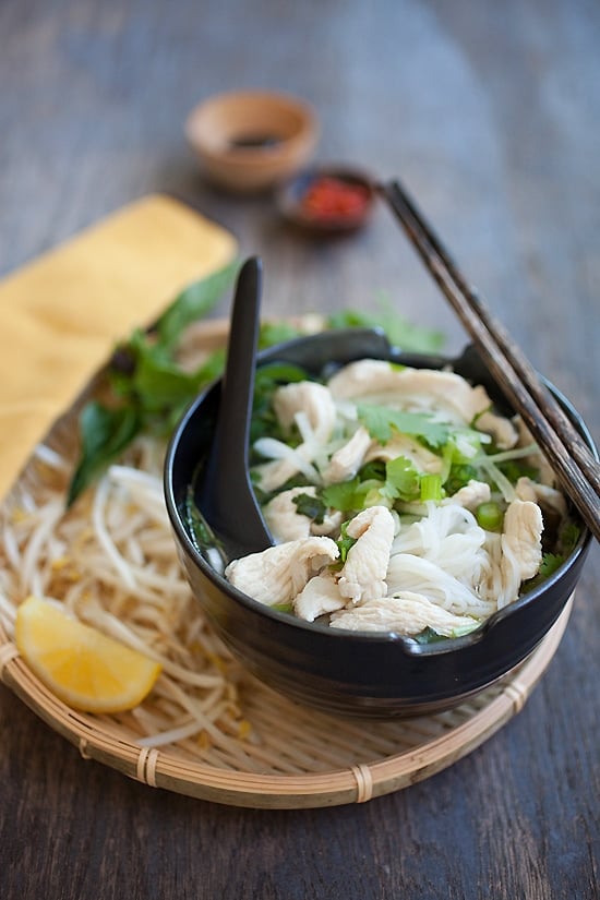 Vietnamese chicken pho recipe, with delicious rice noodles in a bowl and topped with herbs.