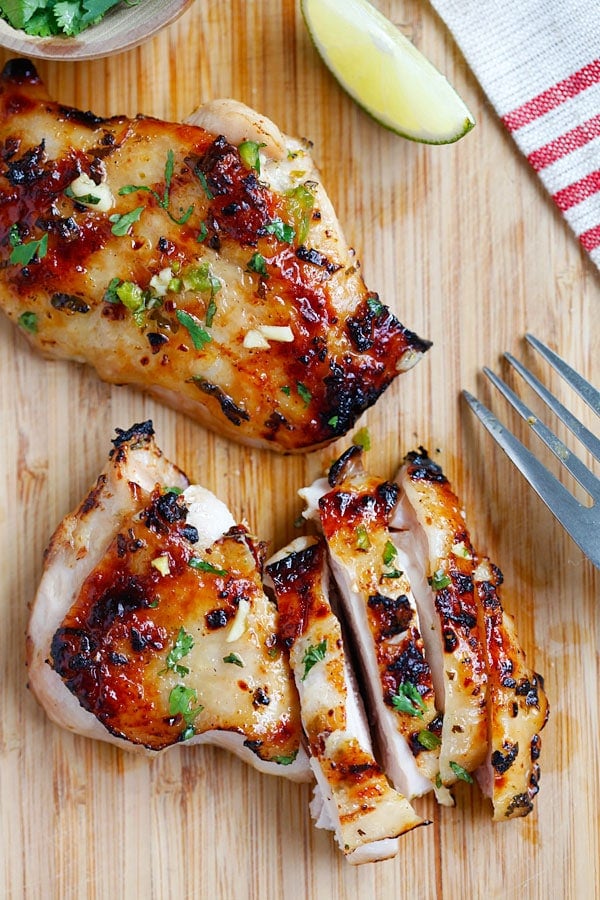 Asian style Chili lime chicken sliced and ready to serve on a wooden chopping board.