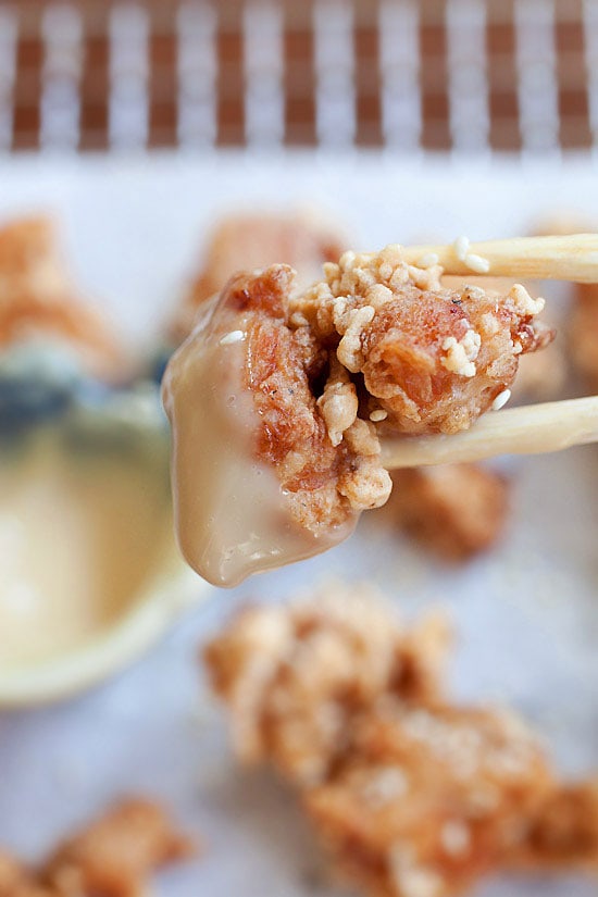 A piece of Crispy and Crunchy Japanese fried chicken picked with a pair of chopsticks dipped with mayo miso dipping sauce.