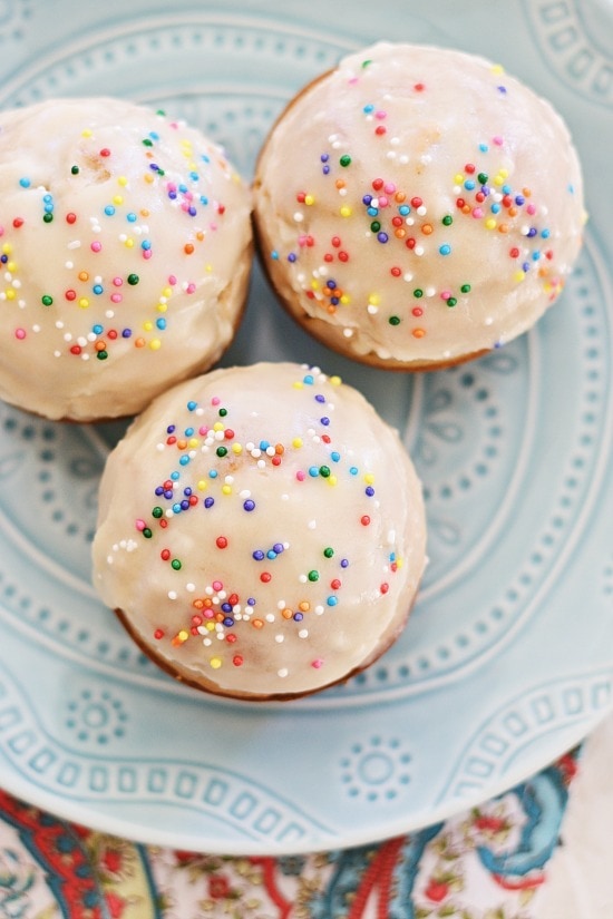 Easy and quick homemade glazed doughnut muffins topped with rainbow sprinkles.