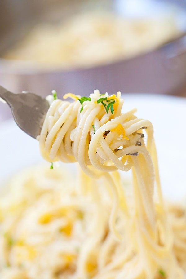 Delicious Garlic Noodles with shredded Parmesan cheese on a fork.