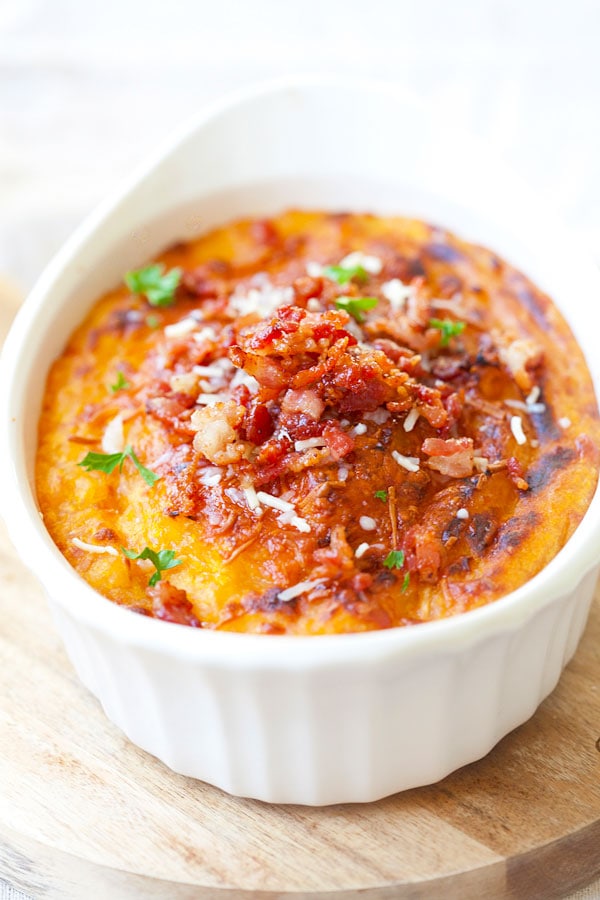 Baked mashed potatoes loaded with parmesan cheese, bacon and pumpkin in serving dish.