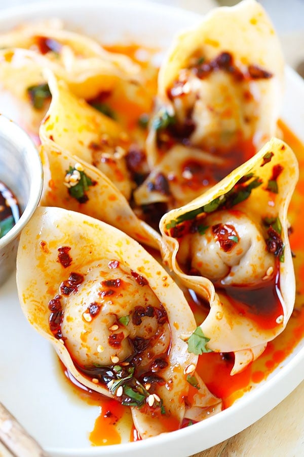 Des quenelles à l'huile rouge épicée du Sichuan faites maison et une sauce au vinaigre noir sur une assiette.