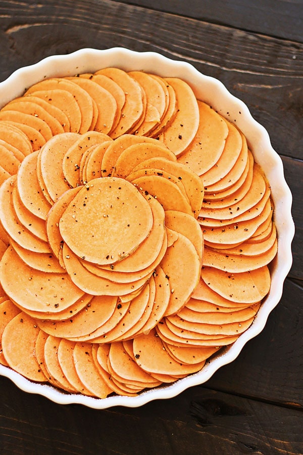 Sliced sweet potato and added seasonings in a bowl ready to be baked.