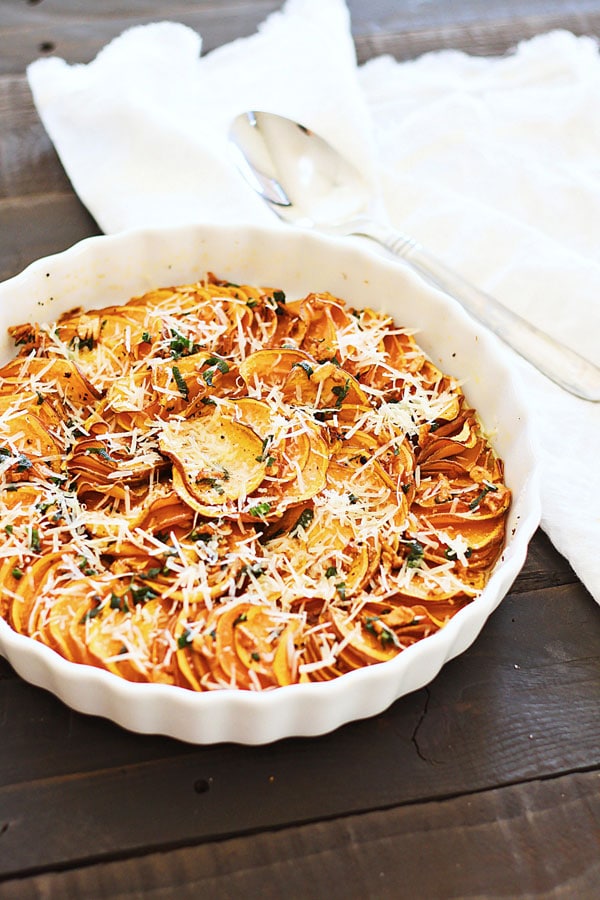 Sweet potato bake with cheese, sage and butter sauce in a serving bowl.