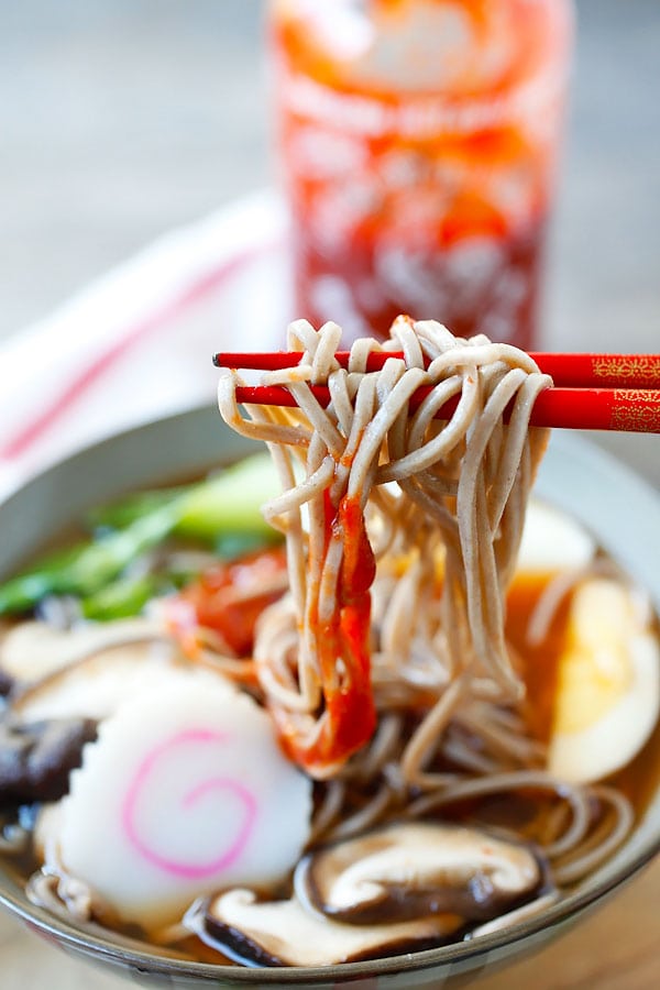 Homemade Spicy Sriracha Soup Soba Noodle picked with a pair of red chopsticks.