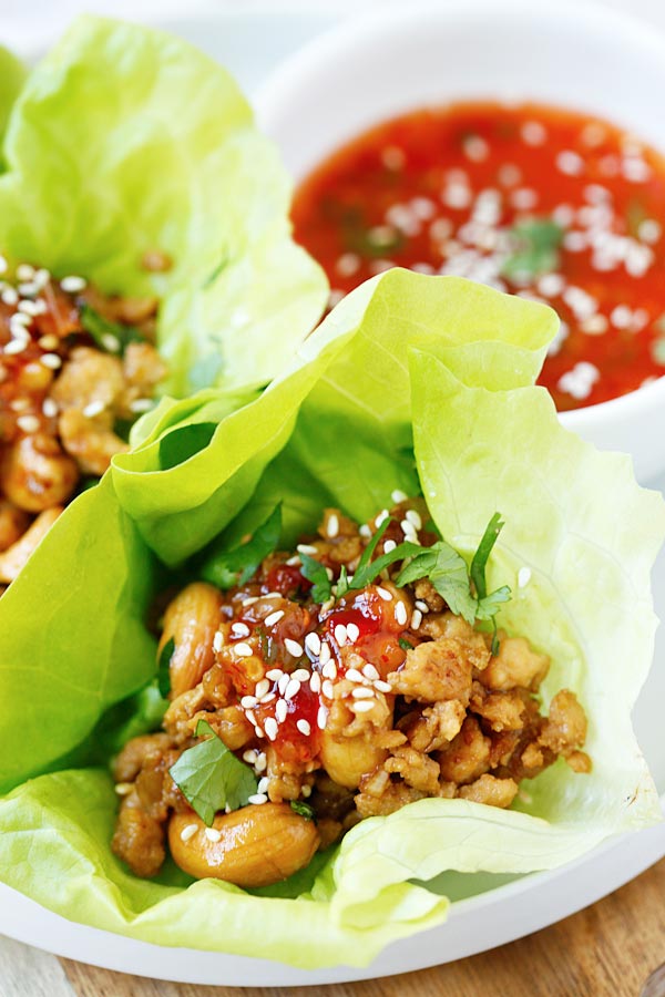 Thai Chicken Lettuce Wraps wrapped in butter lettuce with sweet chili sauce, sesame seeds, cashews, and cilantro.