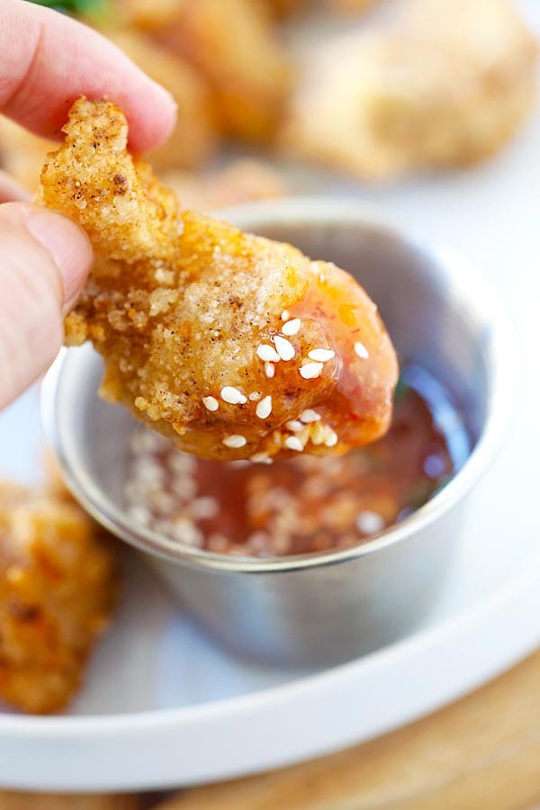 Asian Popcorn Chicken nugget dipped in red dipping sauce.