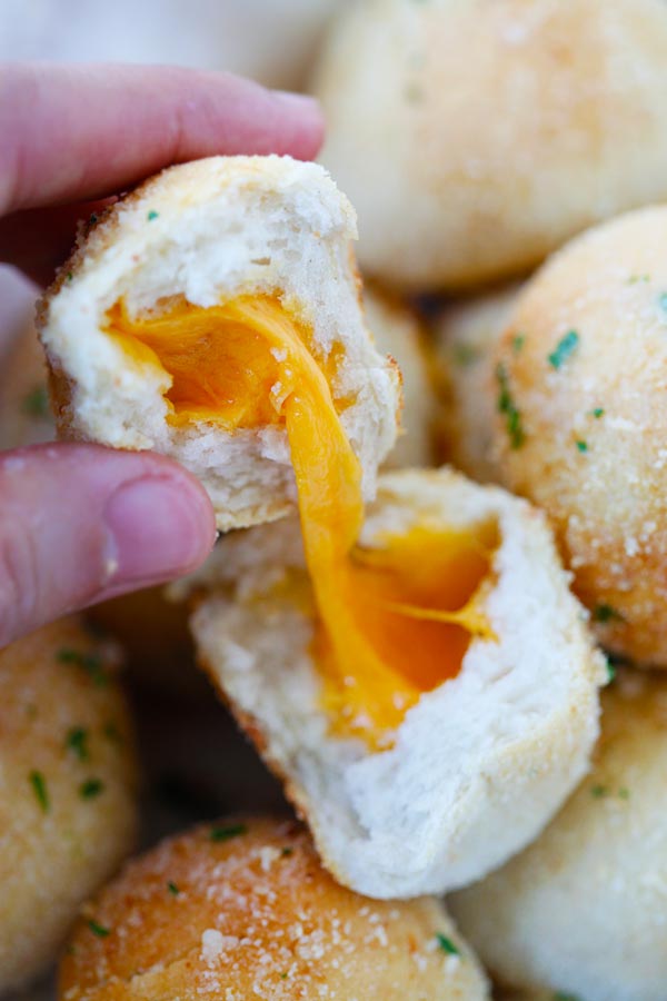Close up Garlic Cheddar Cheese Bombs in half, loaded with melted cheddar cheese.