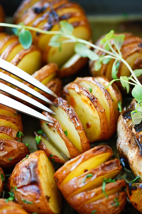 Sliced Garlic Herb Roasted Potatoes with herb, olive oil butter and lemon in baking tray ready to serve.