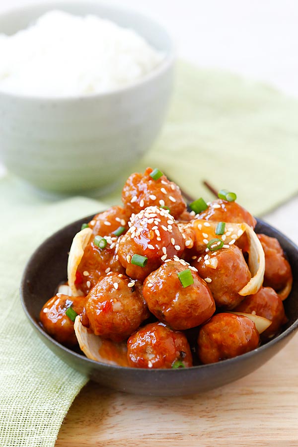 Delicious homemade meat balls covered in a sweet and sour sauce and onions in a bowl.