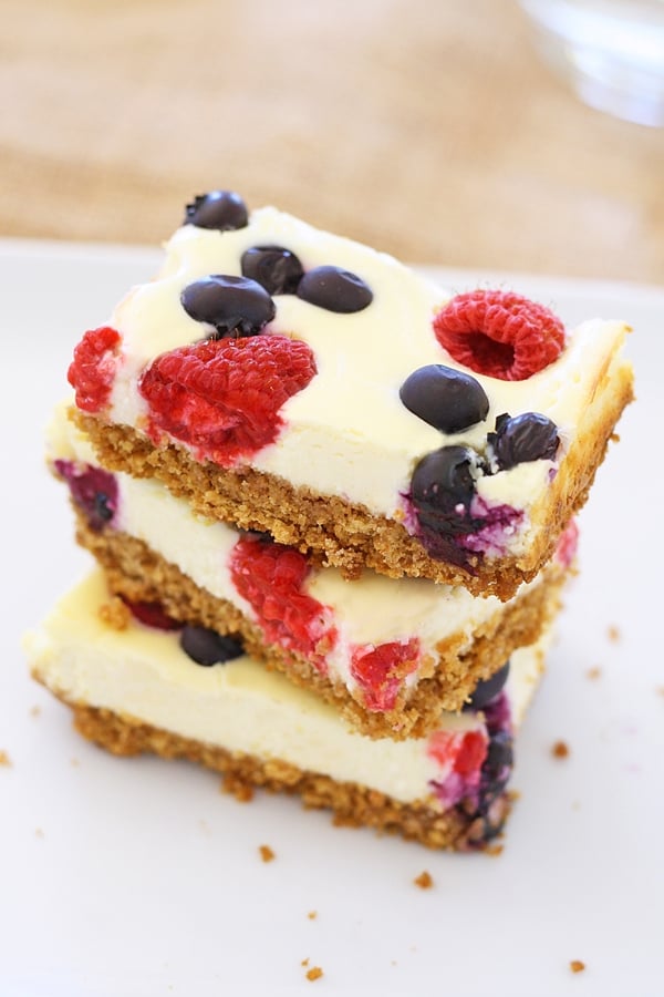Easy and delicious homemade baked berry cheesecake bars stacked together.