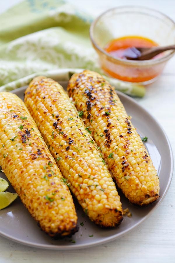 Buttery grilled sweet corn with honey sriracha butter, ready to serve.
