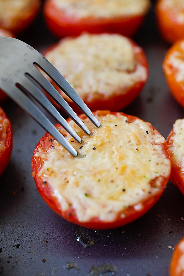 Close up olive oil Parmesan cheese roasted tomatoes poked by a fork.