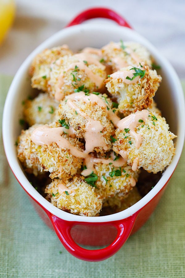 Parmesan Baked Cauliflower coated with Parmesan cheese and panko bread crumbs in a red serving dish.