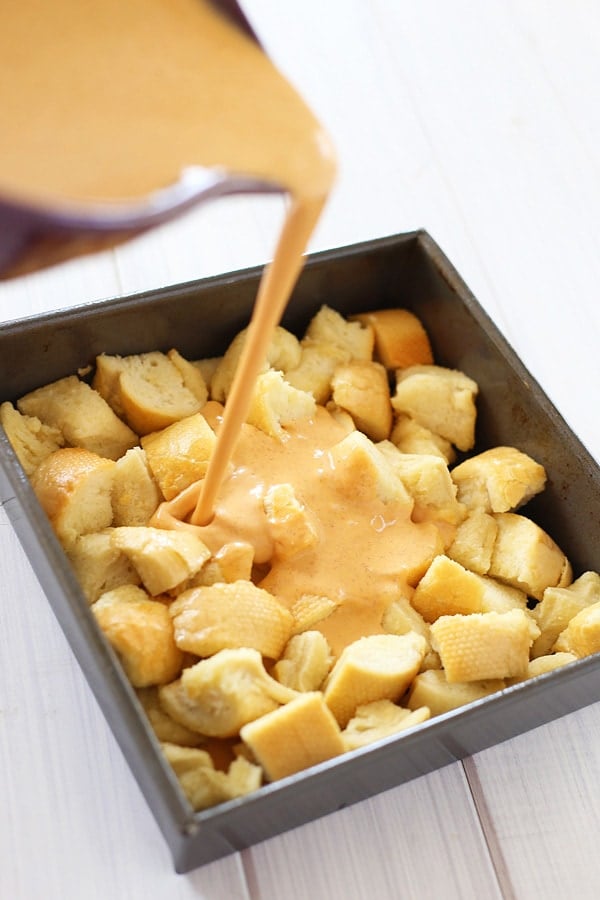 Custard egg poured into leftover bread in cake pan, preparing to bake.