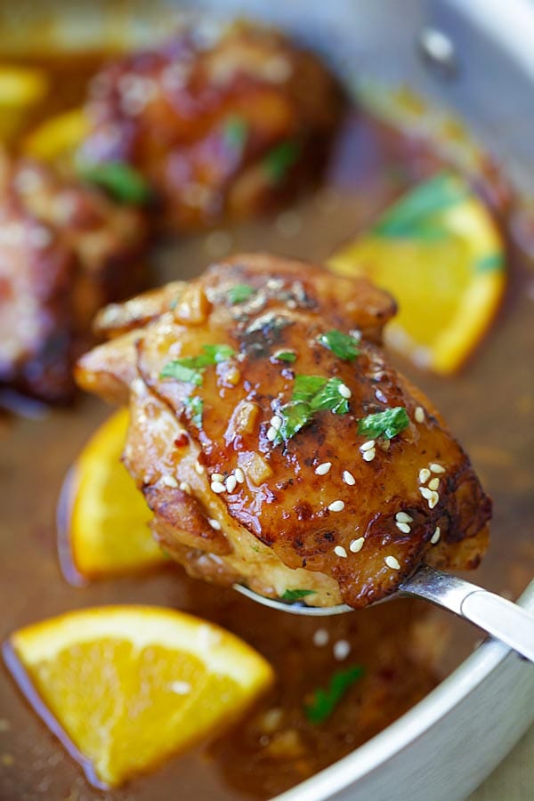Healthy and easy honey orange chicken on a large spoon.