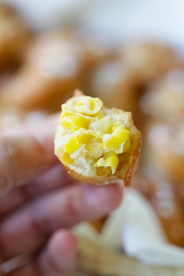 Sweet Corn Fritters in half held in hand.