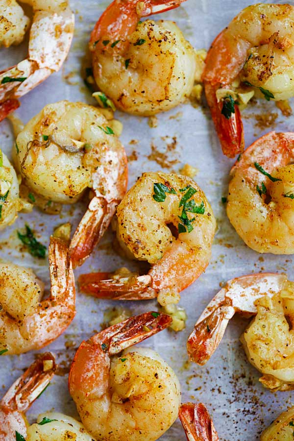 Easy oven roasted shrimp with butter, garlic, herb and serve with cocktail sauce on a baking sheet.