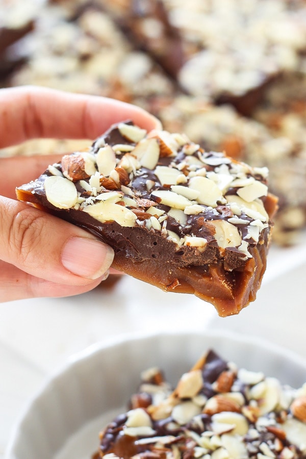 A piece of festive almond toffee held in hand.
