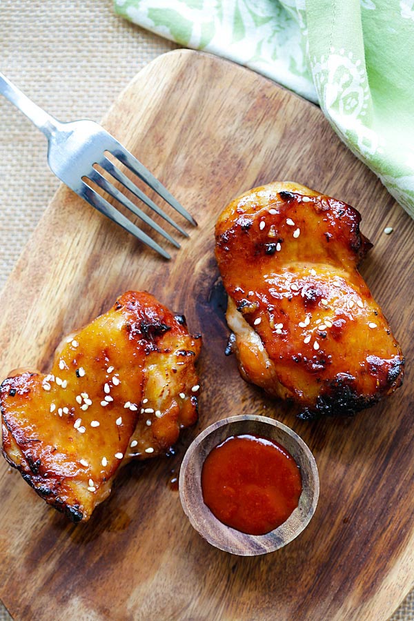 Grilled chicken with honey sriracha marinade on a wooden chopping board.