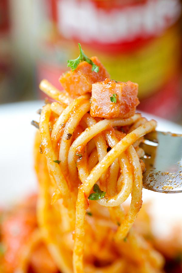 Close up spaghetti pasta with spam and tomato sauce picked with a fork.