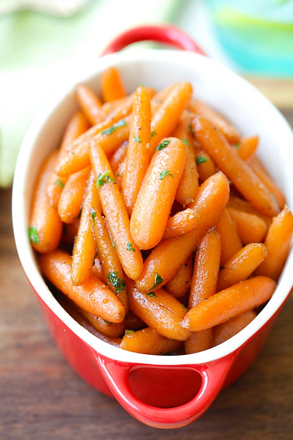 Carottes confites au sucre brun servies dans un plat de service rouge.