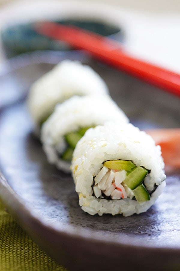 California roll sushi or California maki roll, ready to serve with a pair of red Japanese chopsticks.