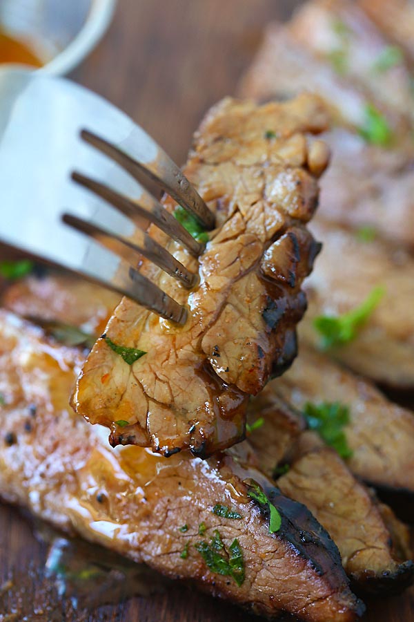 Char grilled Flank Steak topped with honey sriracha butter glaze poked with a fork.