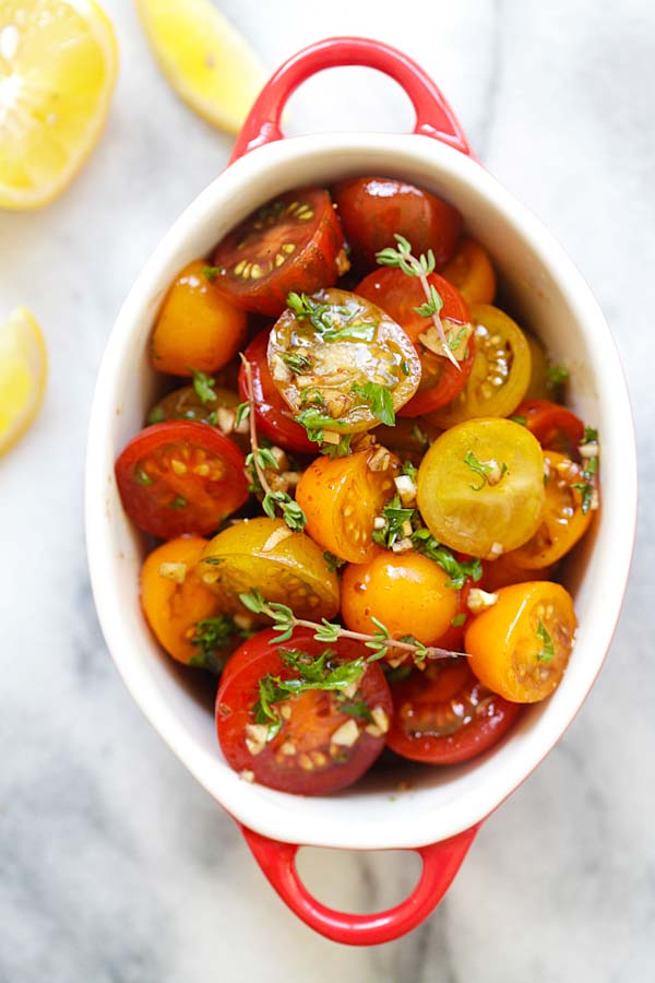 Healthy tomatoes marinated with olive oil, balsamic vinegar and herbs in a serving dish.