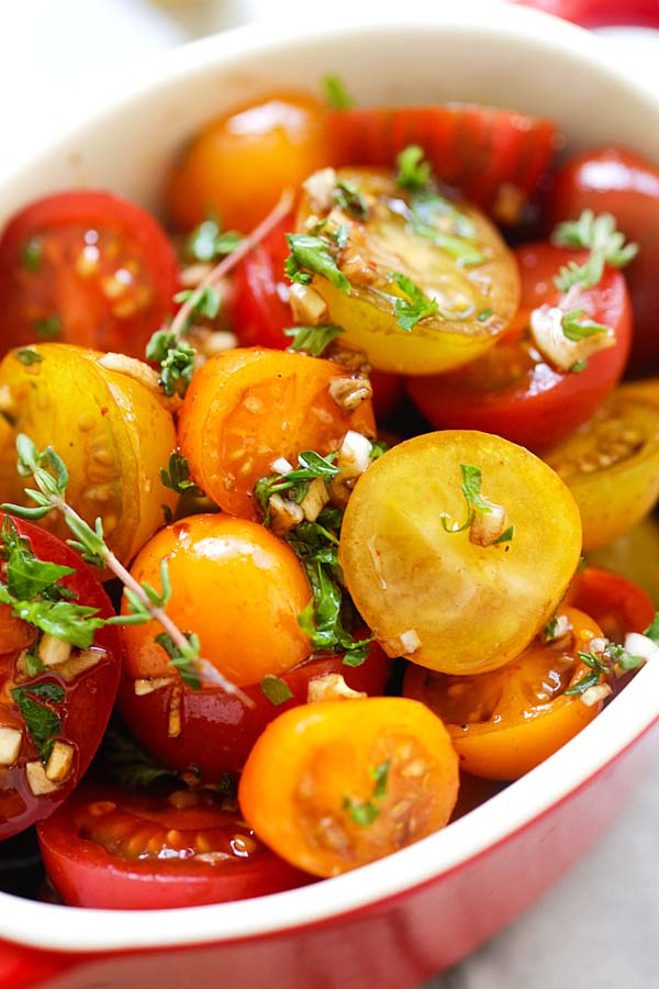 Close up marinated tomatoes in a red serving dish.