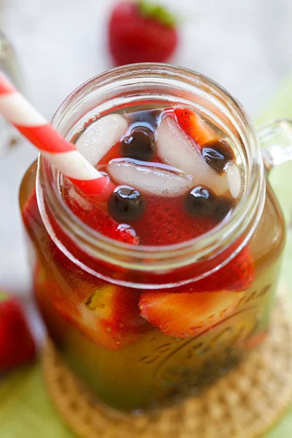 Taiwanese strawberry green tea with fresh sliced strawberries and boba pearls served in a jar glass.