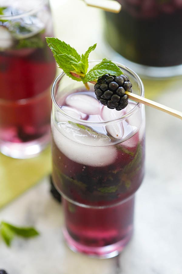 Easy blackberry mojito cocktail, served in a glass with ice, mint leaves and fresh blackberries in wooden stick.