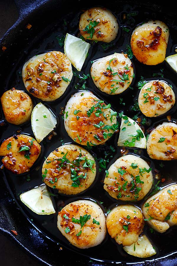 Top down view of brown butter honey garlic scallops with garlic sauce in a skillet ready to serve.