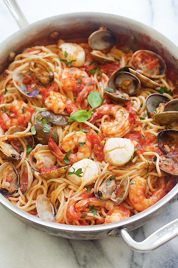 Homemade Italian seafood pasta with scallops, shrimps and clams in a silver pot.