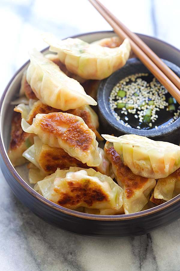 Shrimp gyoza filled with shrimp and cabbage in a serving dish with a side of gyoza dipping sauce.
