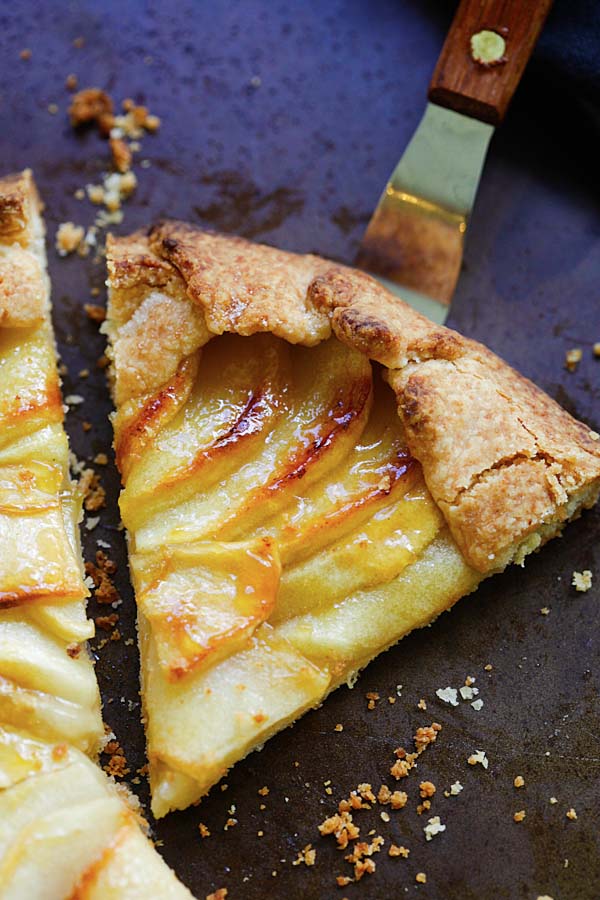 Slice of homemade oven-baked apple tart with scalloped apples in buttery, flaky crust, ready to serve.