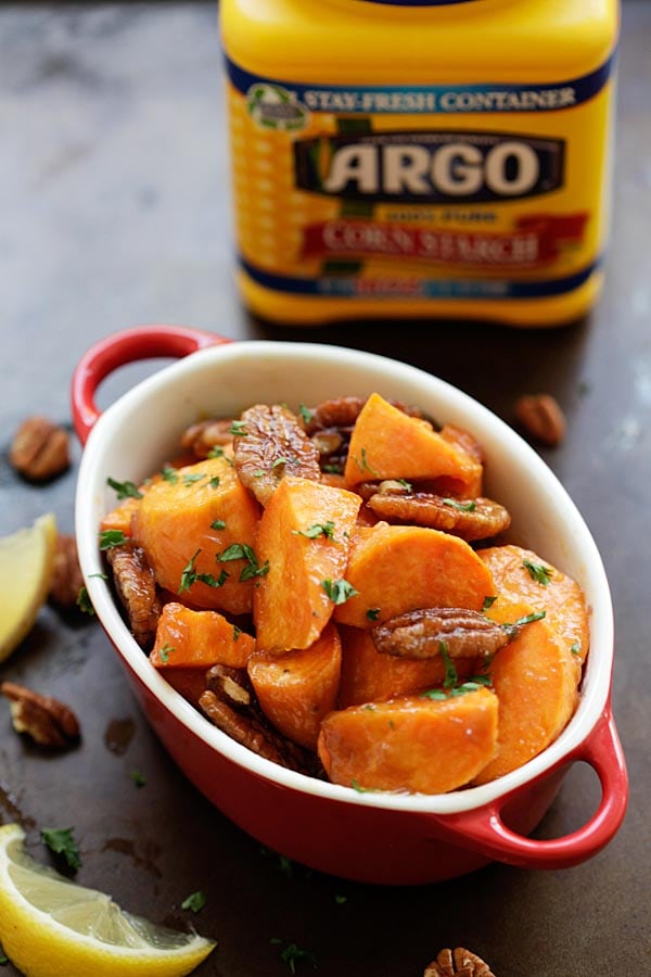 Easy and delicious oven-roasted sweet potatoes with a sticky sweet maple glaze plus nutty pecan served in a serving dish.