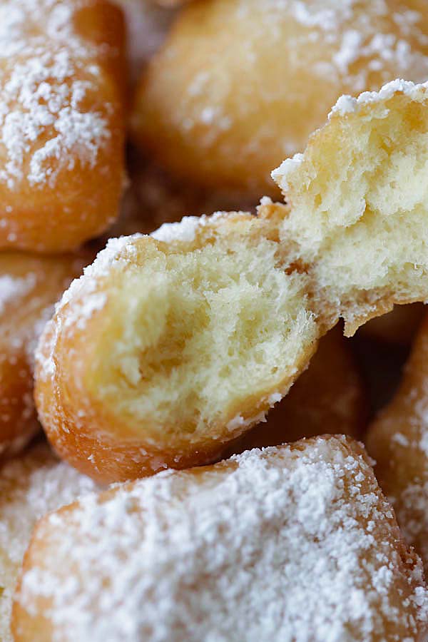 Take a bite of a soft, pillowy, fluffy and airy beignet donut dusted with powdered sugar.