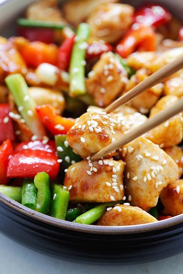 Easy Asian chicken stir fry with Annie Chun's teriyaki sauce and Korean Gochujang in a serving dish, with a pair of chopsticks picking up a piece of chicken.