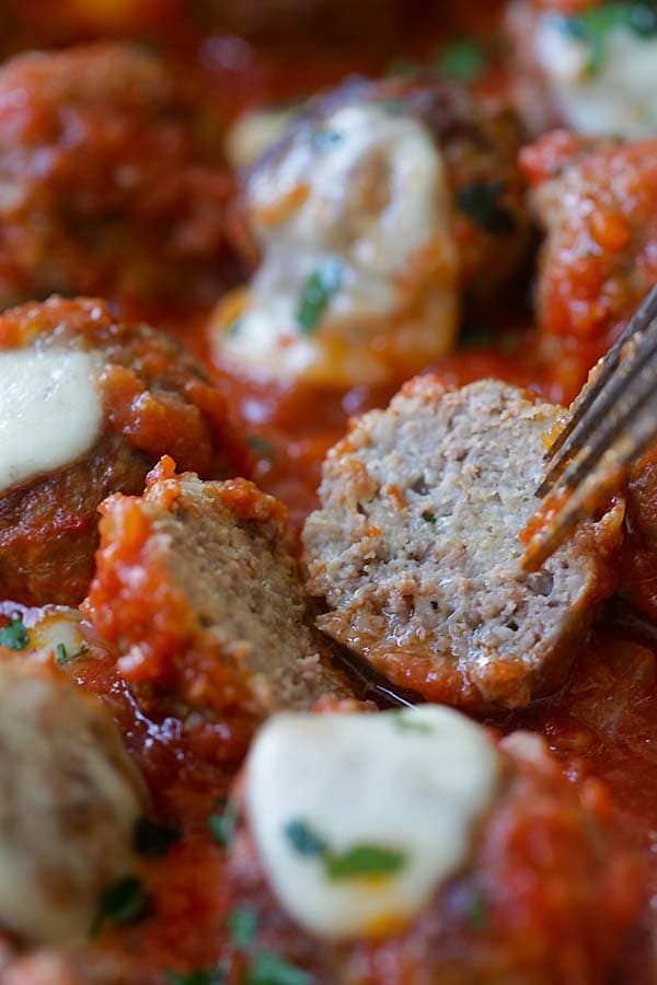 Easy meatball casserole with beef meatballs, one cut in half.