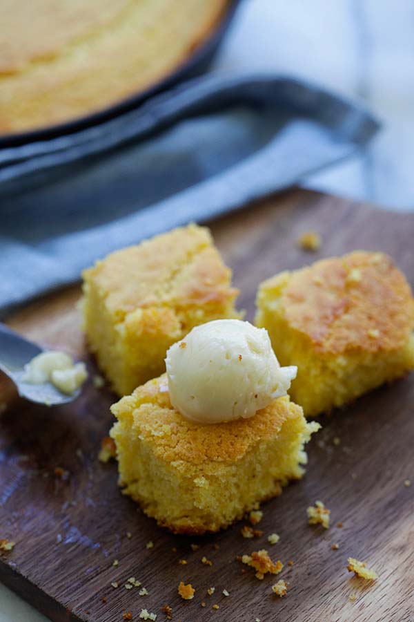 Easy baked corn bread on a wooden chopping board topped with honey butter.