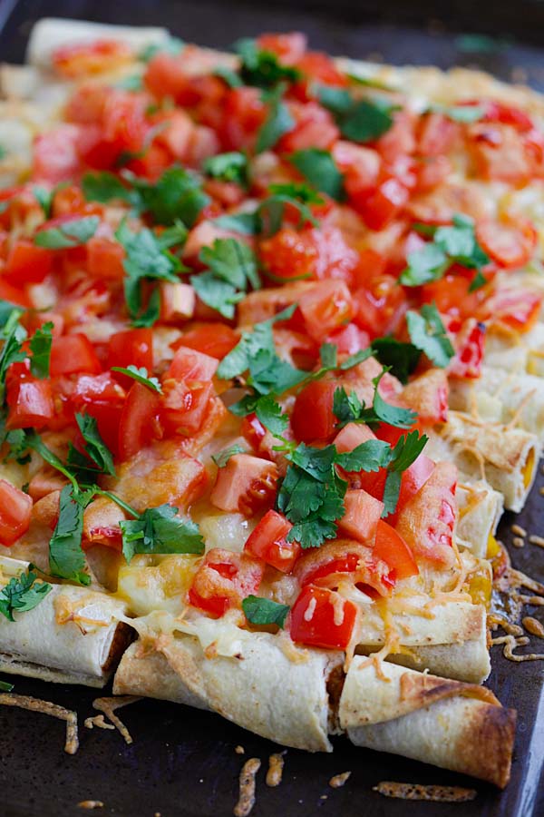 Tasty baked Mexican style rolled tacos with tomatoes, onions, bell peppers and cheese.